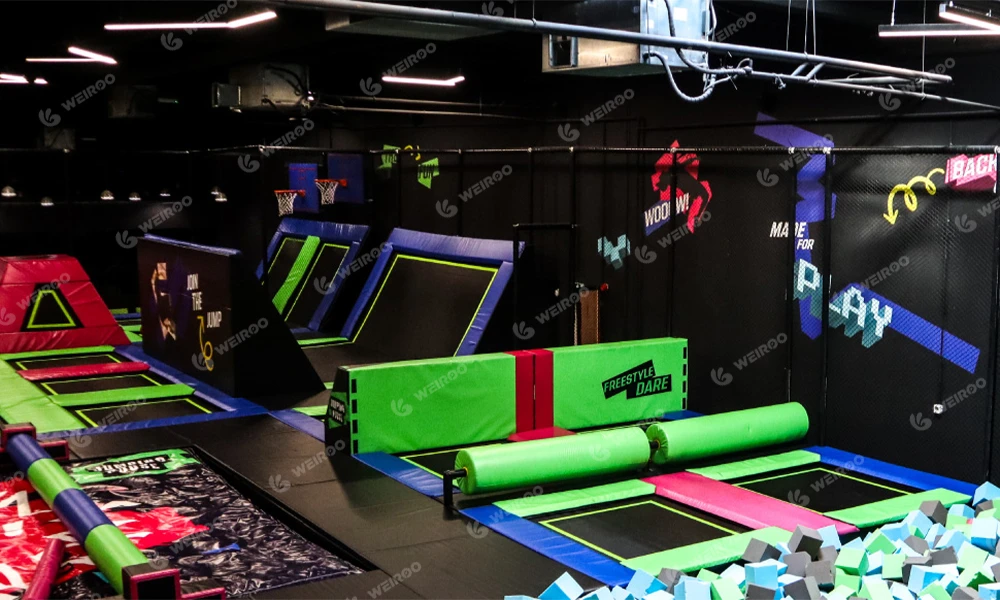 Large free jump zone with parkour obstacles in a black and neon themed park.