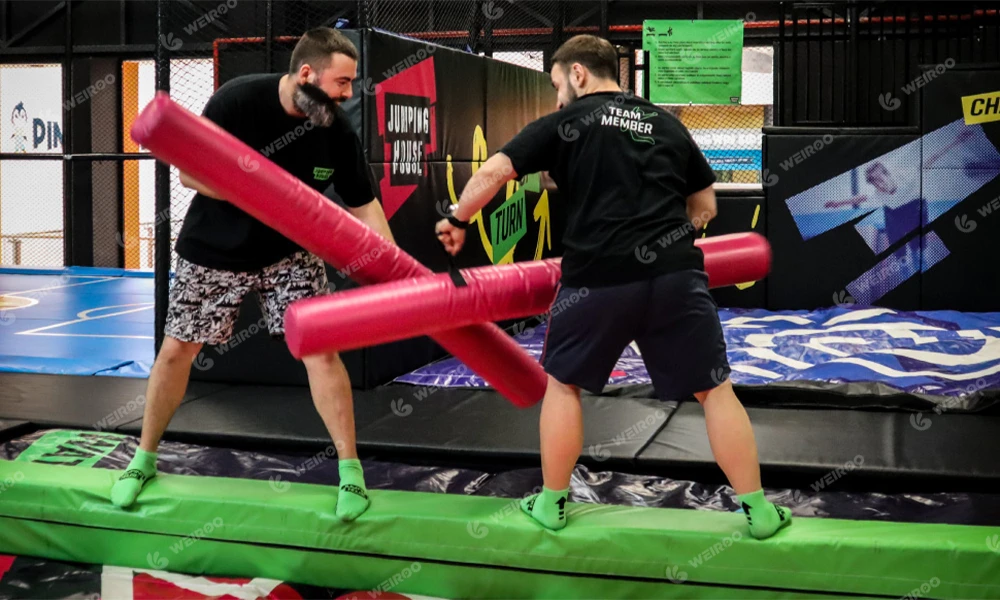 Competitive battle beam game over foam pit for trampoline parks.