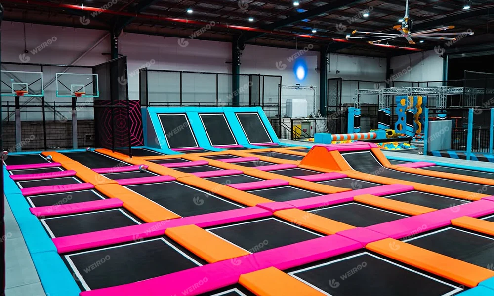 Indoor trampoline zone featuring ninja course and foam pit airbag.