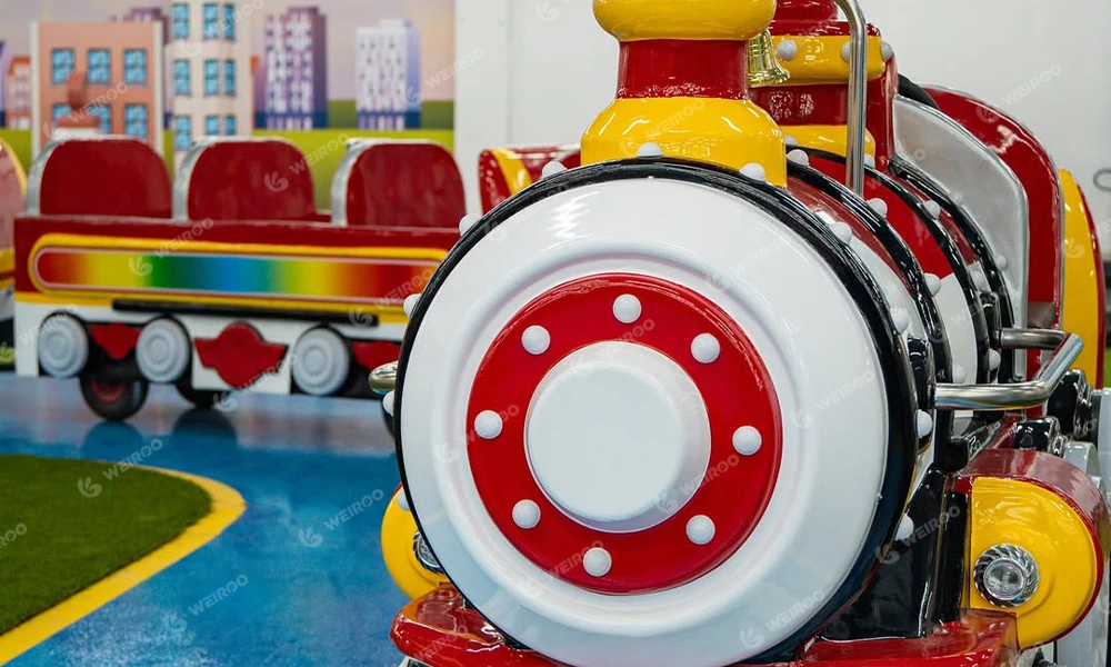Electric mini train attraction for toddlers in indoor playground.