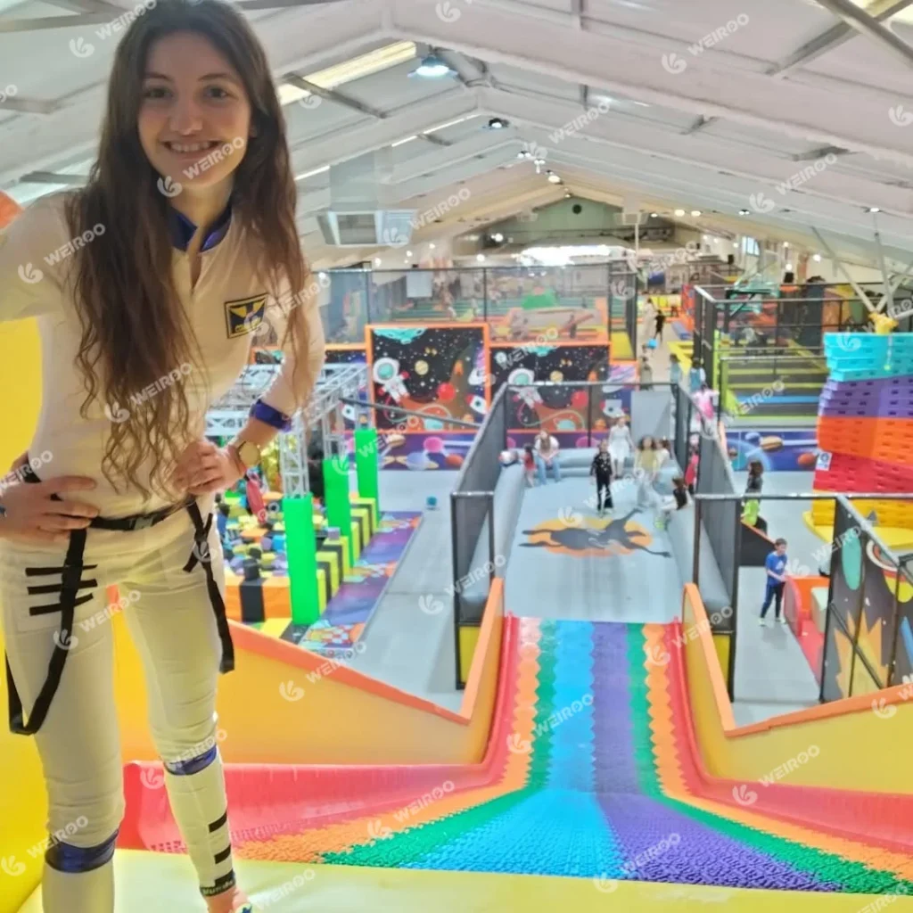 Massive rainbow wave slide at Mundo Jump Park with astronaut staff.