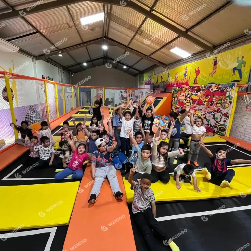 Group of happy children playing in the trampoline zone during a birthday party.