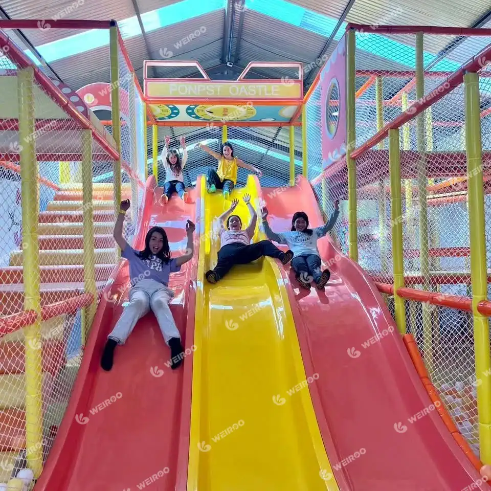 Kids sliding down a triple lane rainbow wave slide at Happy Jump.