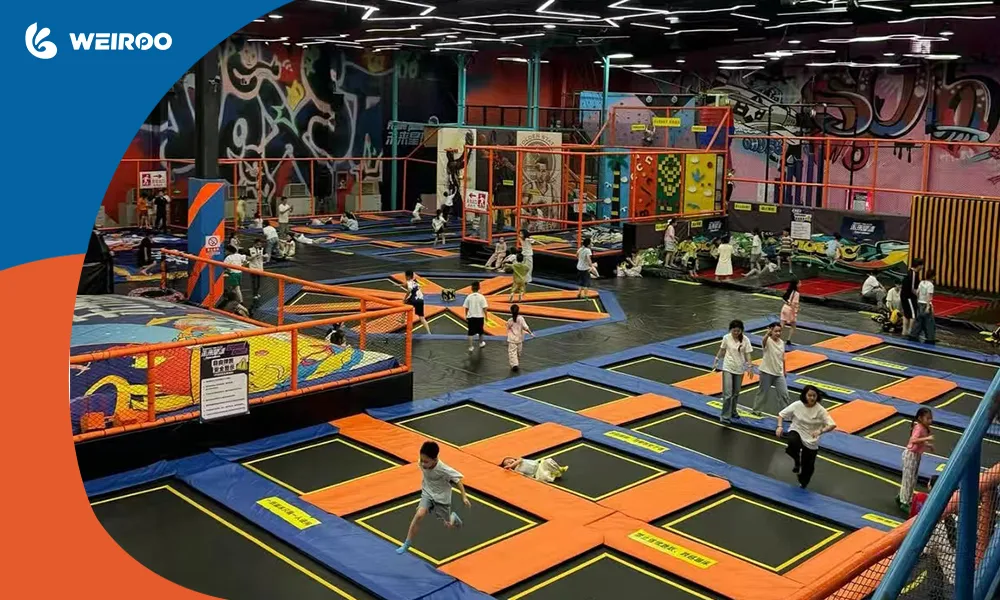 Wide view of an active commercial trampoline park design showing multiple jump zones and the mandatory high ceiling clearance required for safety compliance.