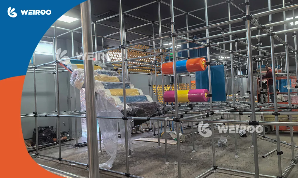 Weiroo Play engineers installing galvanized steel frame structure for an indoor playground project.