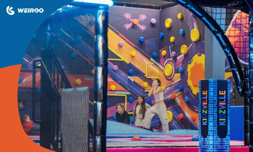 Children having fun in a colorful indoor playground featuring trampolines and a climbing wall, ideal for hosting profitable birthday parties.