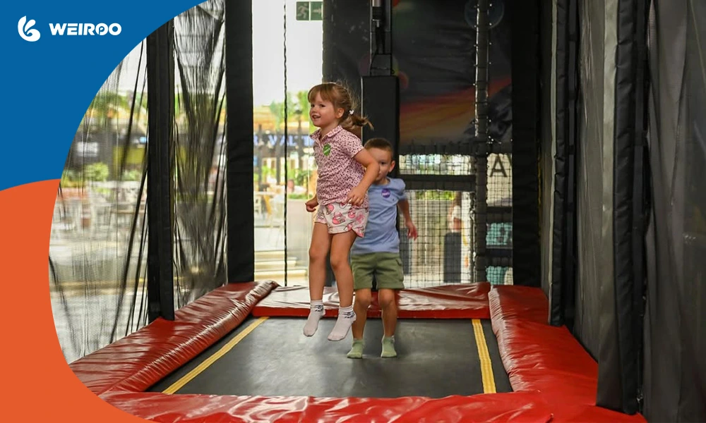 Young children jumping on a safe, commercial-grade indoor trampoline enclosed with strict safety netting.
