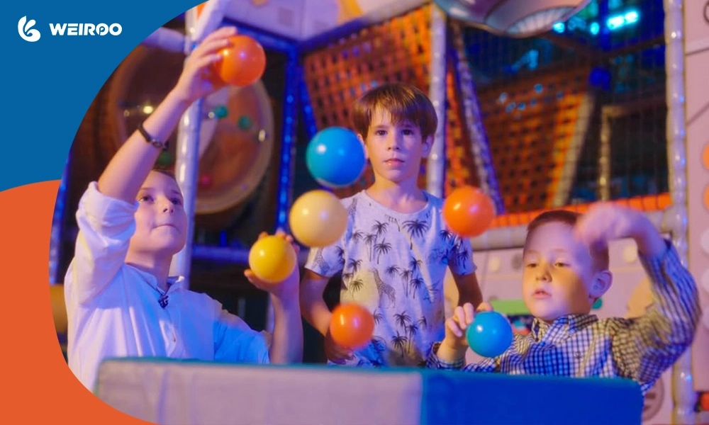 Children interacting with colorful balls at an indoor soft play area, illustrating engaging mechanical play features.