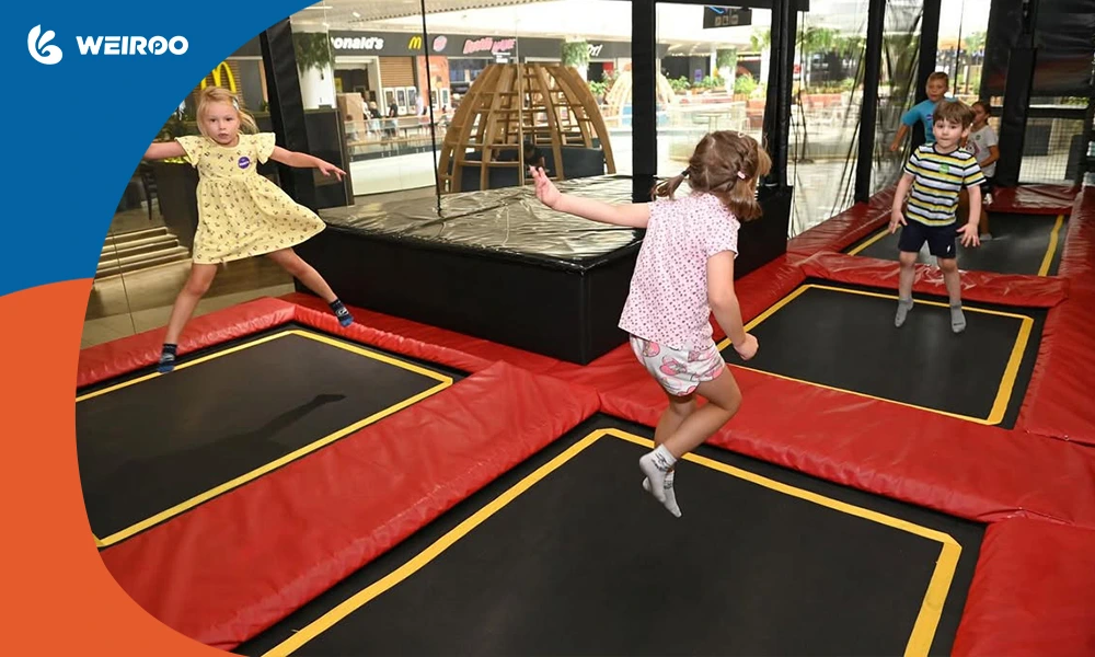 Children bouncing on a small interconnected trampoline court within a family entertainment center.