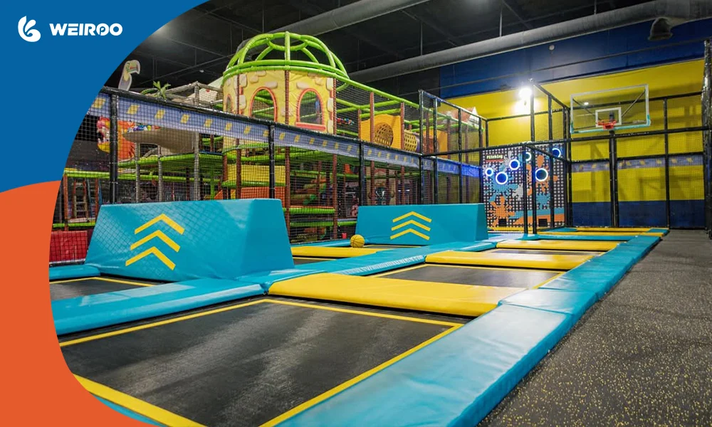 Wide view of a modern trampoline park layout, showcasing interconnected jumping mats, angled trampolines, and strict safety netting.